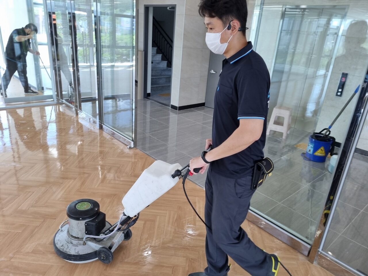 건물 로비 바닥을 폴리셔로 세척하는 작업자 건물 로비 바닥을 폴리셔로 세척하는 작업자